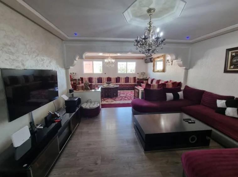Grand salon lumineux et élégant avec double séjour, décoration marocaine moderne, lustres en cristal et parquet, dans un appartement de luxe à Kénitra.